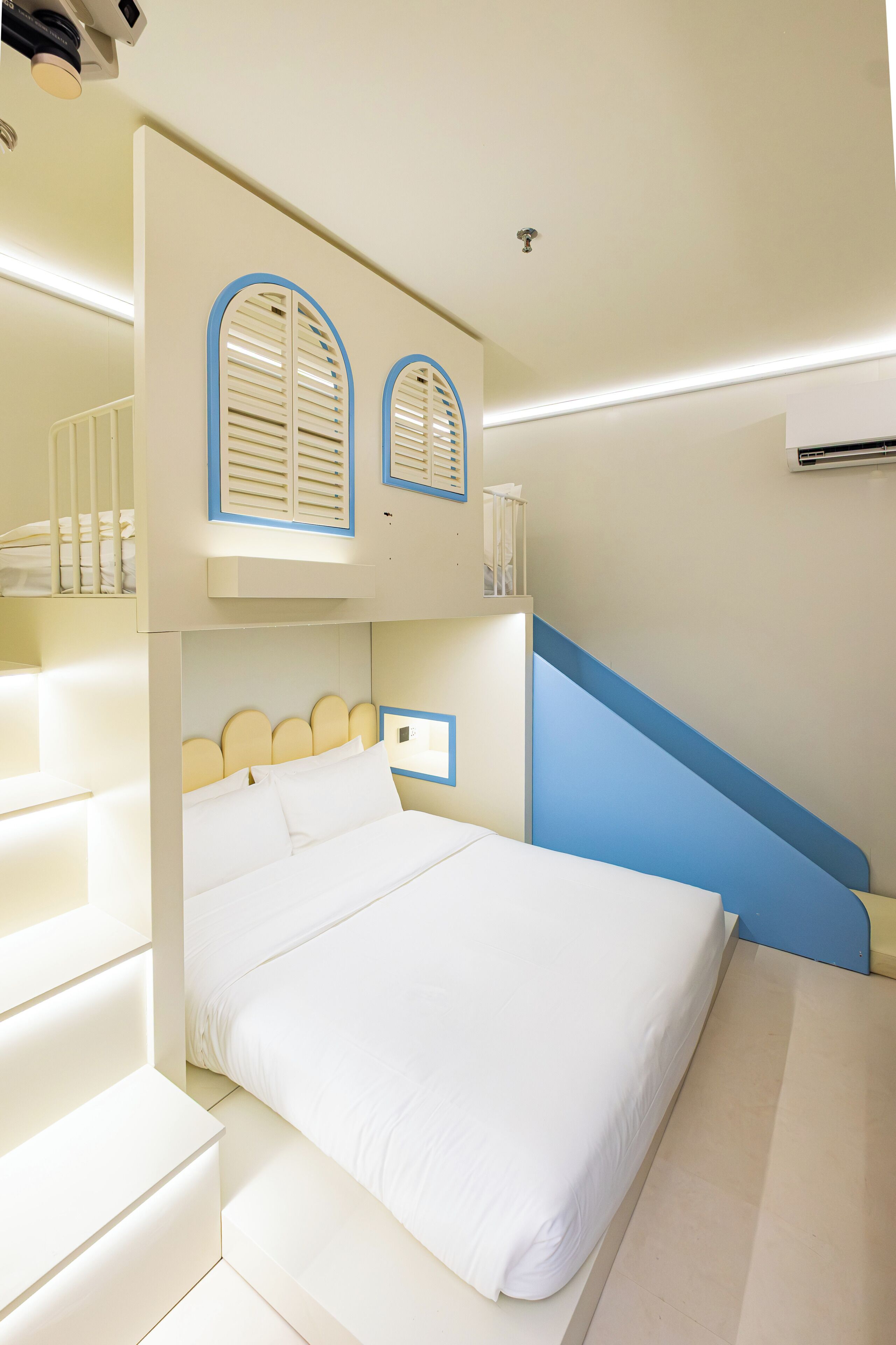 Une chambre d’hôtel avec un lit superposé, un bureau et un escalier.