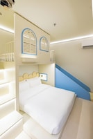 Una habitación de hotel con literas, un escritorio y una escalera.
