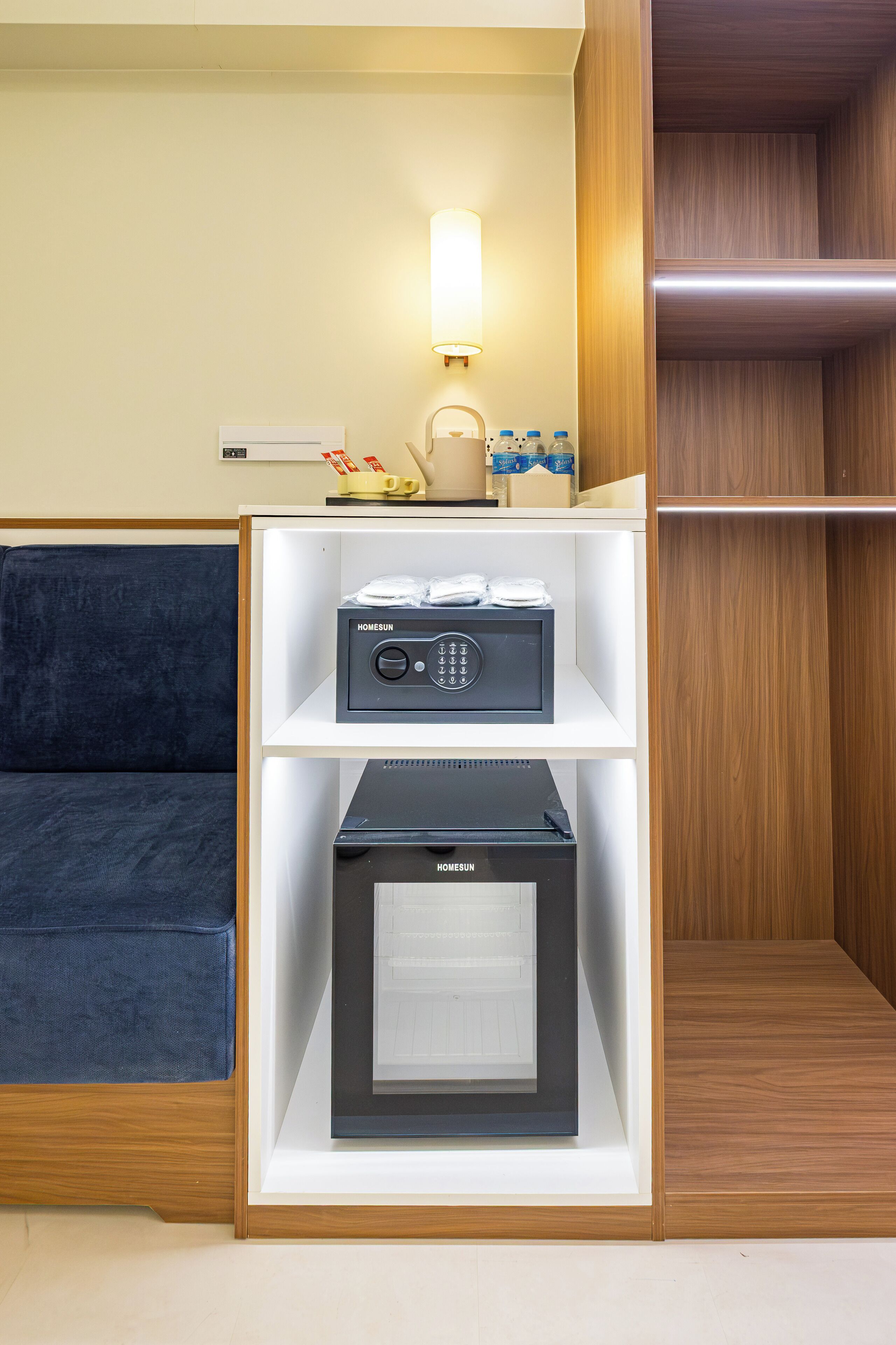 A hotel room with a minibar, a microwave, and a coffee maker on a shelf.