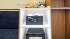 Habitación de hotel con minibar, microondas y cafetera sobre una estantería.