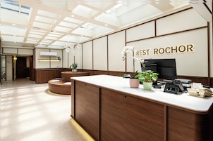 A reception desk with a sign reading 'REST ROCHOR' in a modern interior with wooden paneling and a skylight ceiling.