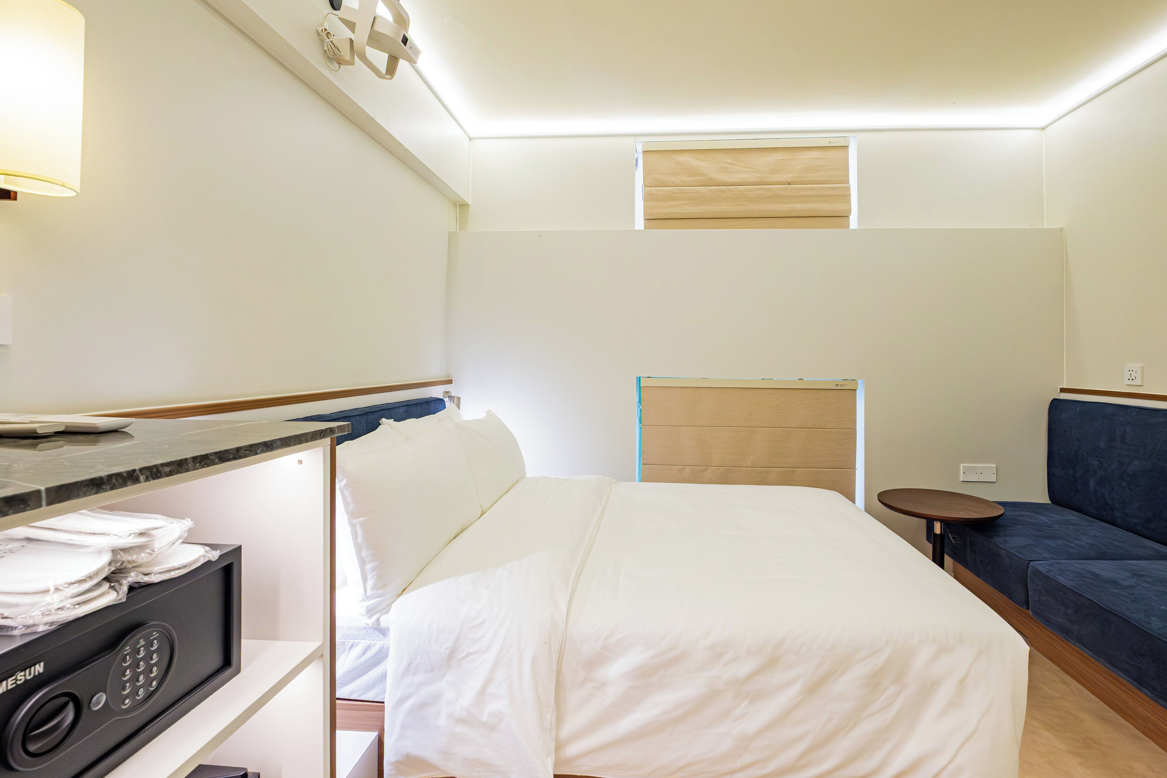 A hotel room with a bed, a desk with a computer, a small table, and a sofa.