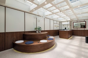 Un área de recepción moderna con un mostrador de madera, asientos y un espejo grande.