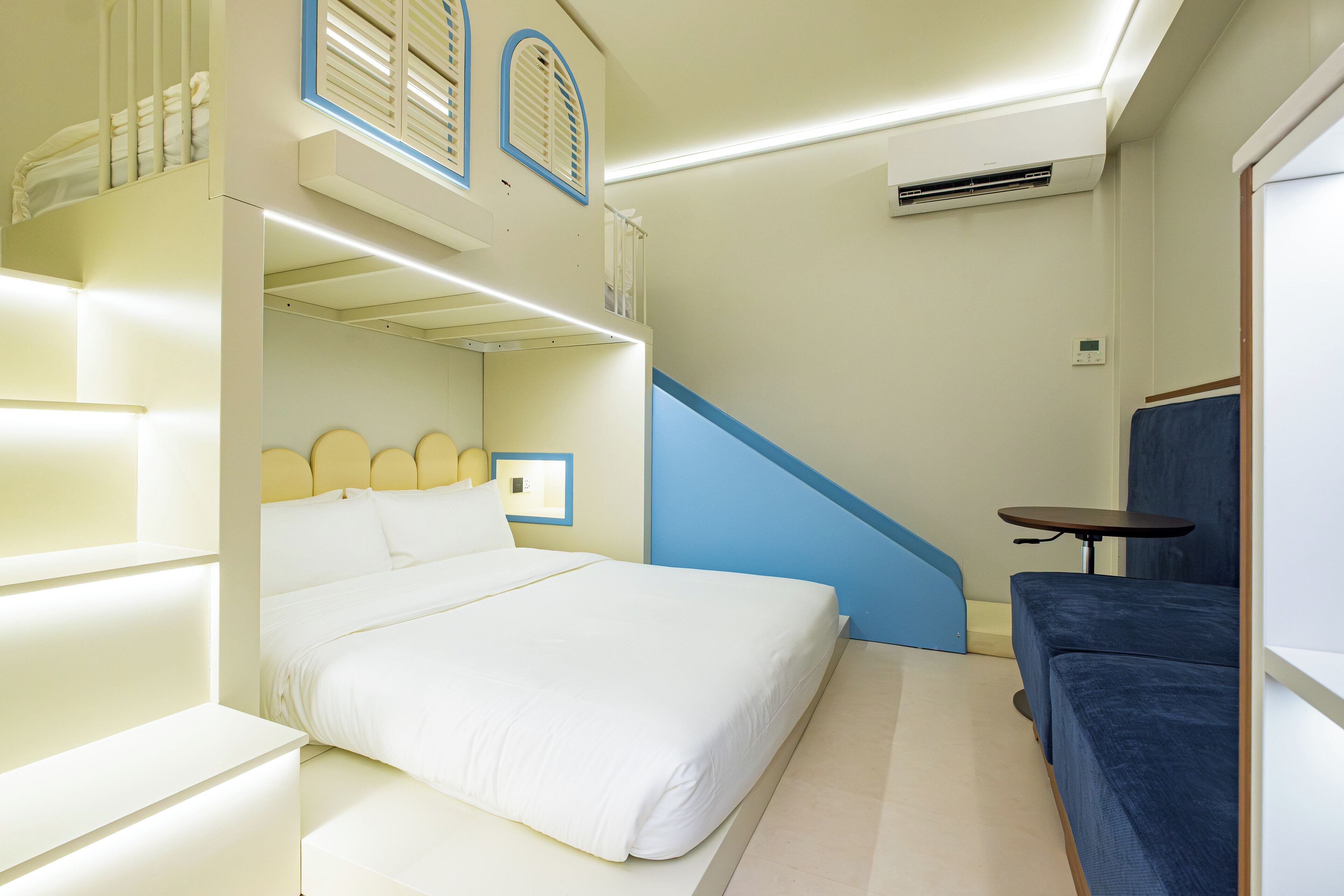 Une chambre d’hôtel comprenant un lit, un coin salon, un escalier et un appareil de climatisation.