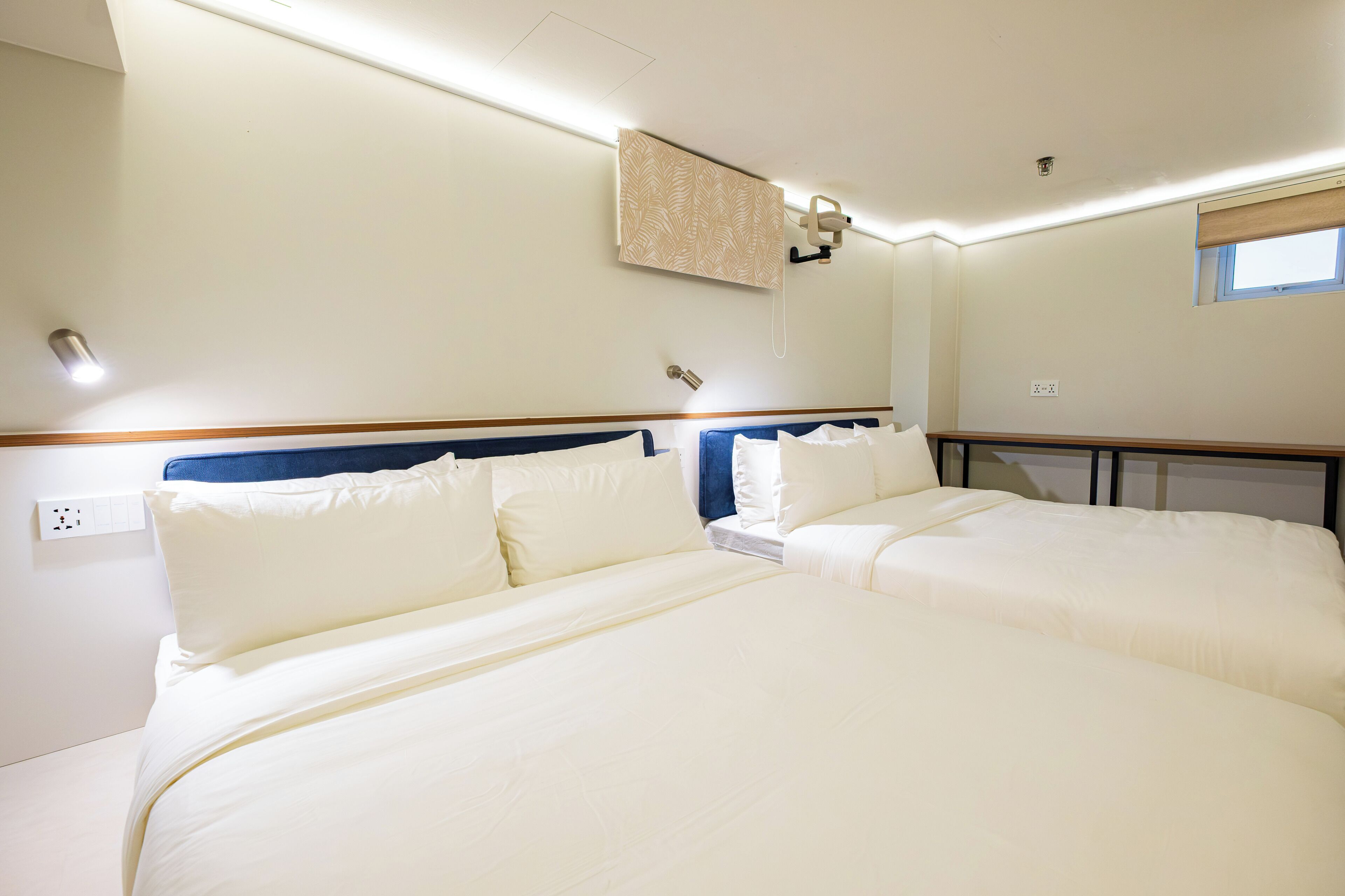 Ein Hotelzimmer mit zwei Betten, einem Fenster und einer Deckenleuchte.