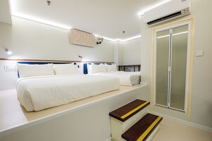 A hotel room with two beds, a wardrobe, a mirror, and a small table.