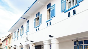 Un hotel con paredes exteriores blancas y contraventanas azules, que presenta un estilo arquitectónico tradicional.