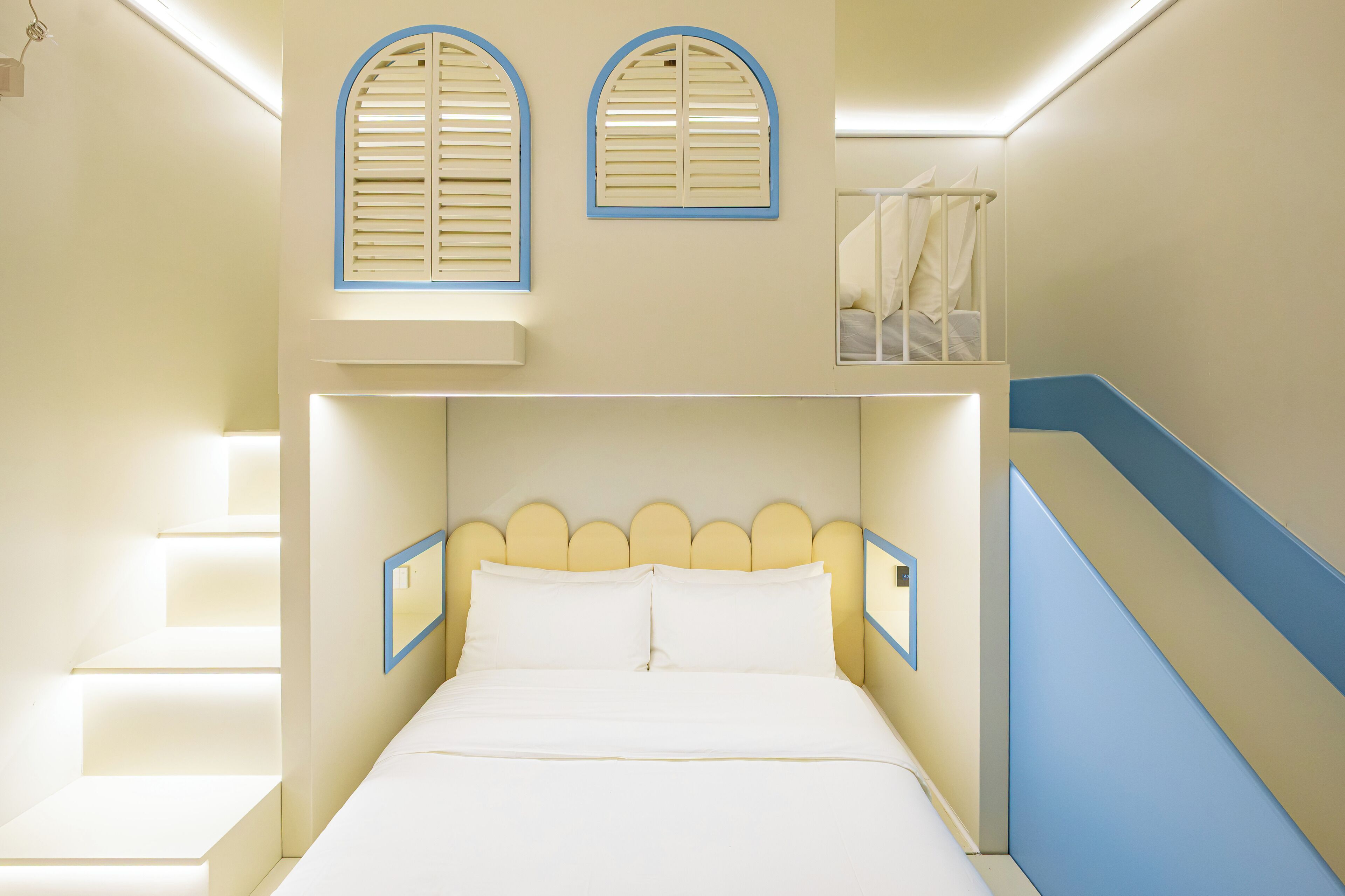 Una habitación con literas, una ventana con persianas y una escalera con detalles azules.