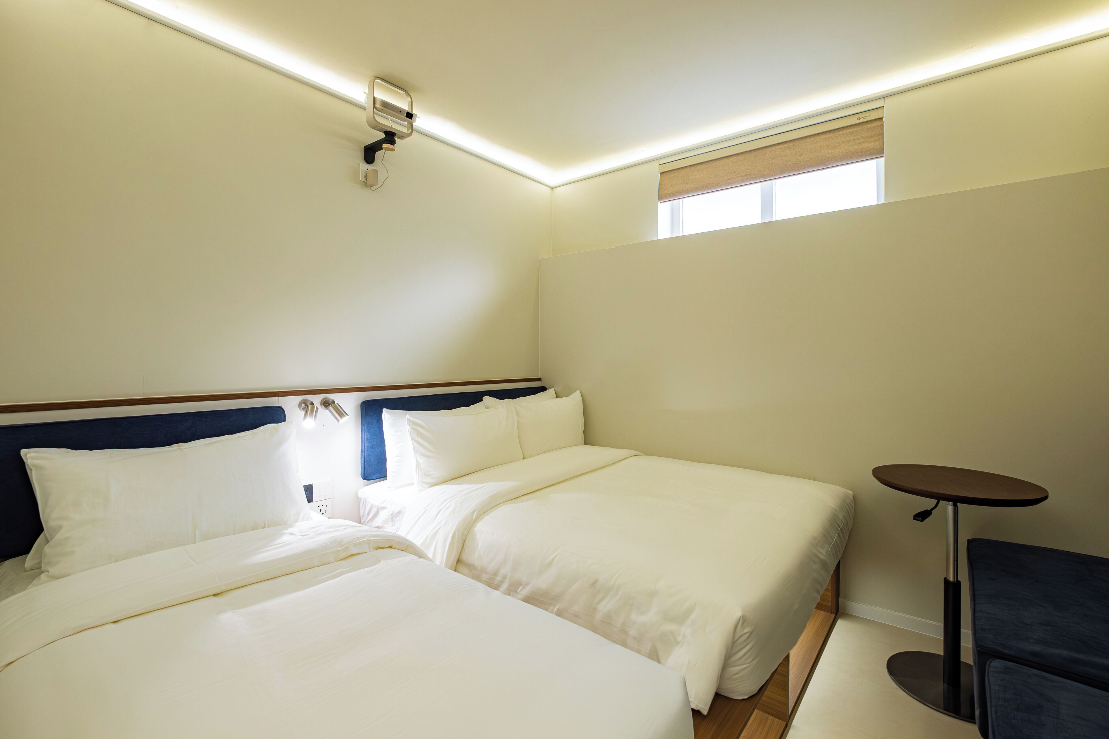 Une chambre d’hôtel avec deux lits, une petite table et une fenêtre.