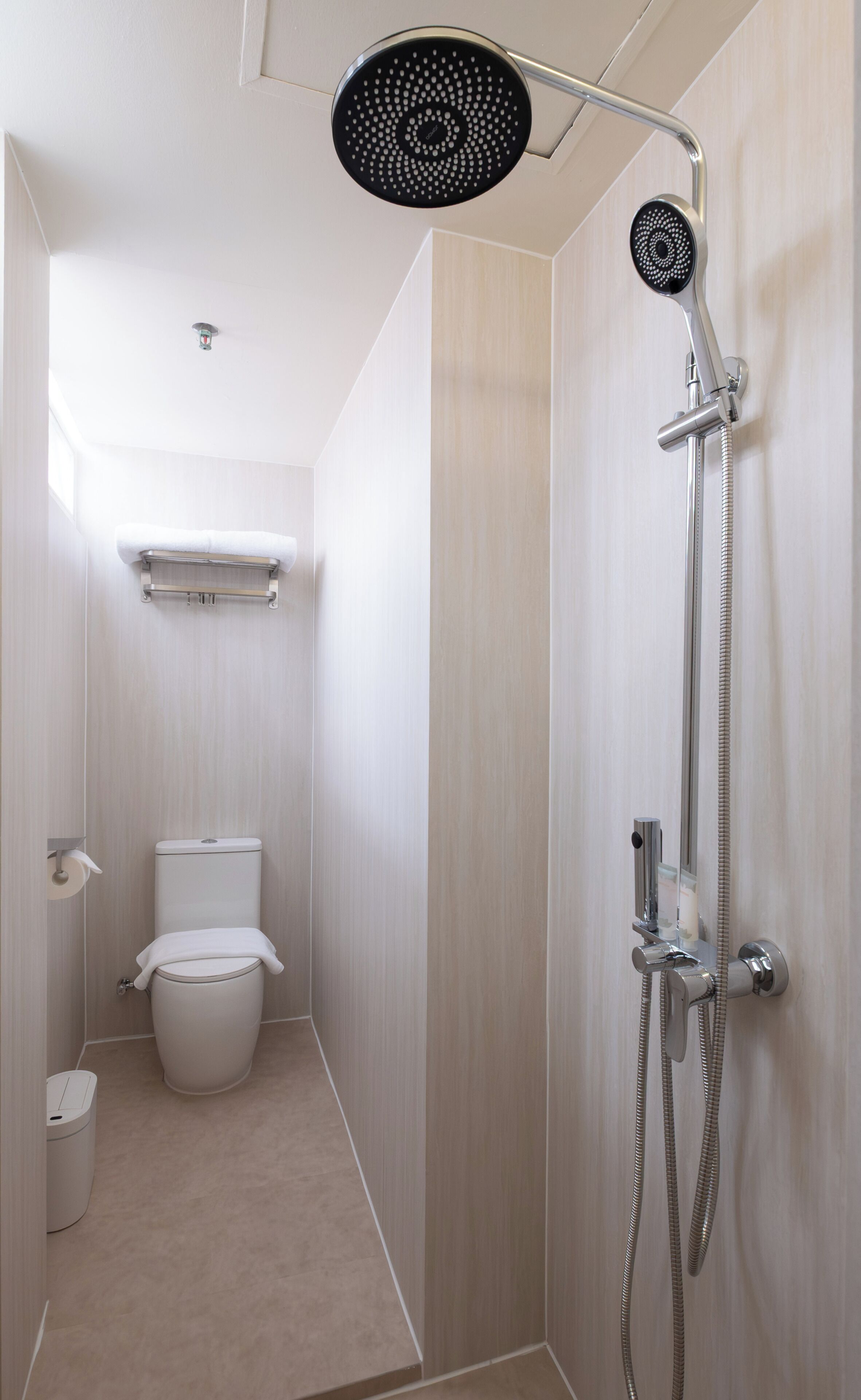 A modern bathroom with a shower, toilet, and a towel rack.