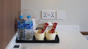 Ein Hotelzimmer mit Nachttisch, einer Wasserflasche, einer Tasse und einer Fernbedienung.