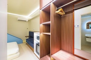 Una habitación moderna con armario empotrado, una zona de estar con sofá azul y una pequeña mesa.