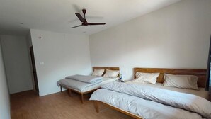 A room with two single beds, a ceiling fan, and a wooden floor.