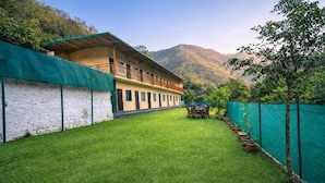 A building with a green roof, a balcony, and a grassy courtyard with potted plants.