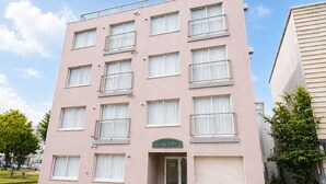 Un edificio de varios pisos con fachada plana, múltiples ventanas y una entrada visible.