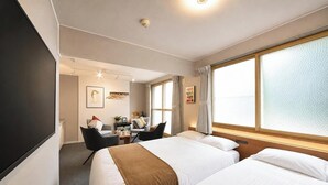 Habitación de hotel con dos camas, un escritorio, una silla y un ventanal grande.