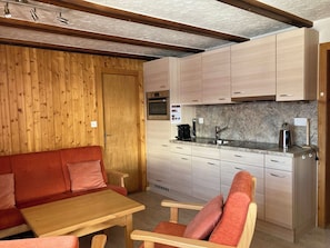 A compact kitchen with wooden cabinets, a built-in oven, and a countertop with a coffee maker. - Chalet Allegra Appartement/Fewo, Dusche, WC 4-Bettwohnung Erdgeschoss by Interhome (Rosswald)
