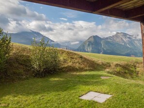 A grassy field with a wooden structure, a mountain range in the background, and a clear sky. - Chalet Allegra Appartement/Fewo, Dusche, WC 4-Bettwohnung Erdgeschoss by Interhome (Rosswald)