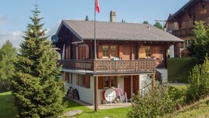 A two-story wooden chalet with a balcony, surrounded by greenery. - Chalet Allegra Appartement/Fewo, Dusche, WC 4-Bettwohnung Erdgeschoss by Interhome (Rosswald)