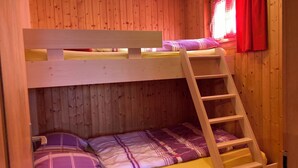 A bunk bed with a wooden ladder, a window with red curtains, and a wooden wall. - Chalet Allegra Appartement/Fewo, Dusche, WC 4-Bettwohnung Erdgeschoss by Interhome (Rosswald)