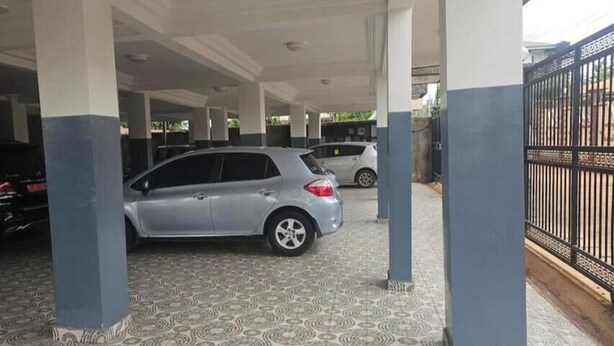 A covered parking area with a patterned floor and a silver car parked in the center. - Luxury Lita Residence (Centre Region)