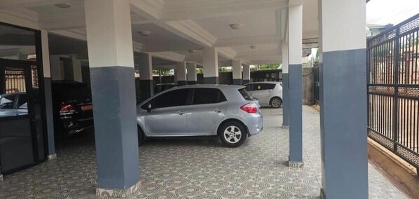Ein überdachter Parkbereich mit gemustertem Boden und einem silbernen Auto in der Mitte.