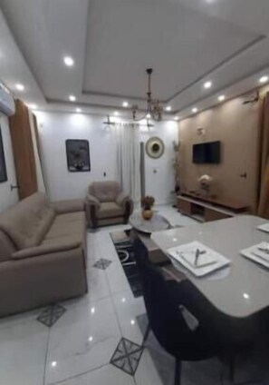 Ein modernes Wohnzimmer mit Sofa, Esstisch und Fernseher.