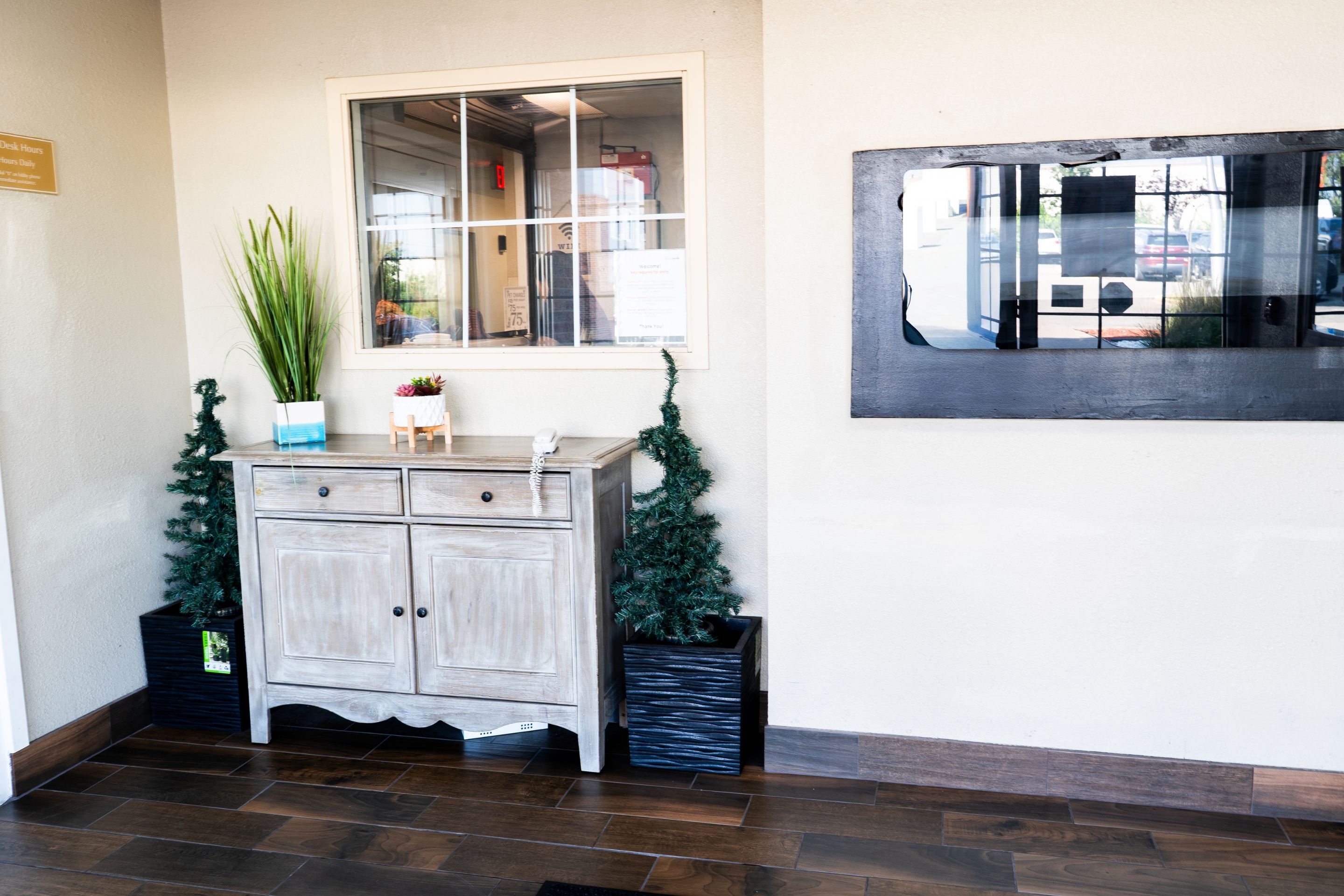 Un área de recepción con un mueble de madera, una planta en maceta y un pequeño árbol de Navidad.