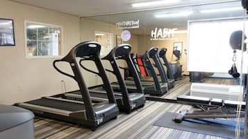 Ein Fitnessstudio mit Laufbändern an der Wand, einem Spiegel und motivierenden Sprüchen.