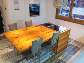 A modern kitchen with a wooden table, chairs, and built-in appliances. - Appartement Binna 4-Bettwohnung, Dusche, WC 3-Bettwohnung, Dusche, WC by Interhome (Rosswald)