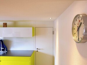 A room with a yellow cabinet, a white door, and a wall-mounted clock. - Appartement Binna 4-Bettwohnung, Dusche, WC 3-Bettwohnung, Dusche, WC by Interhome (Rosswald)