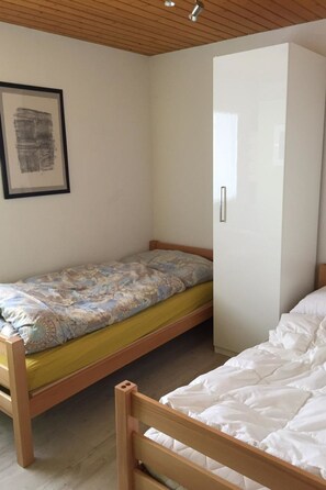 Ein Zimmer mit einem Etagenbett, einem Kleiderschrank und einem gerahmten Bild an der Wand.
