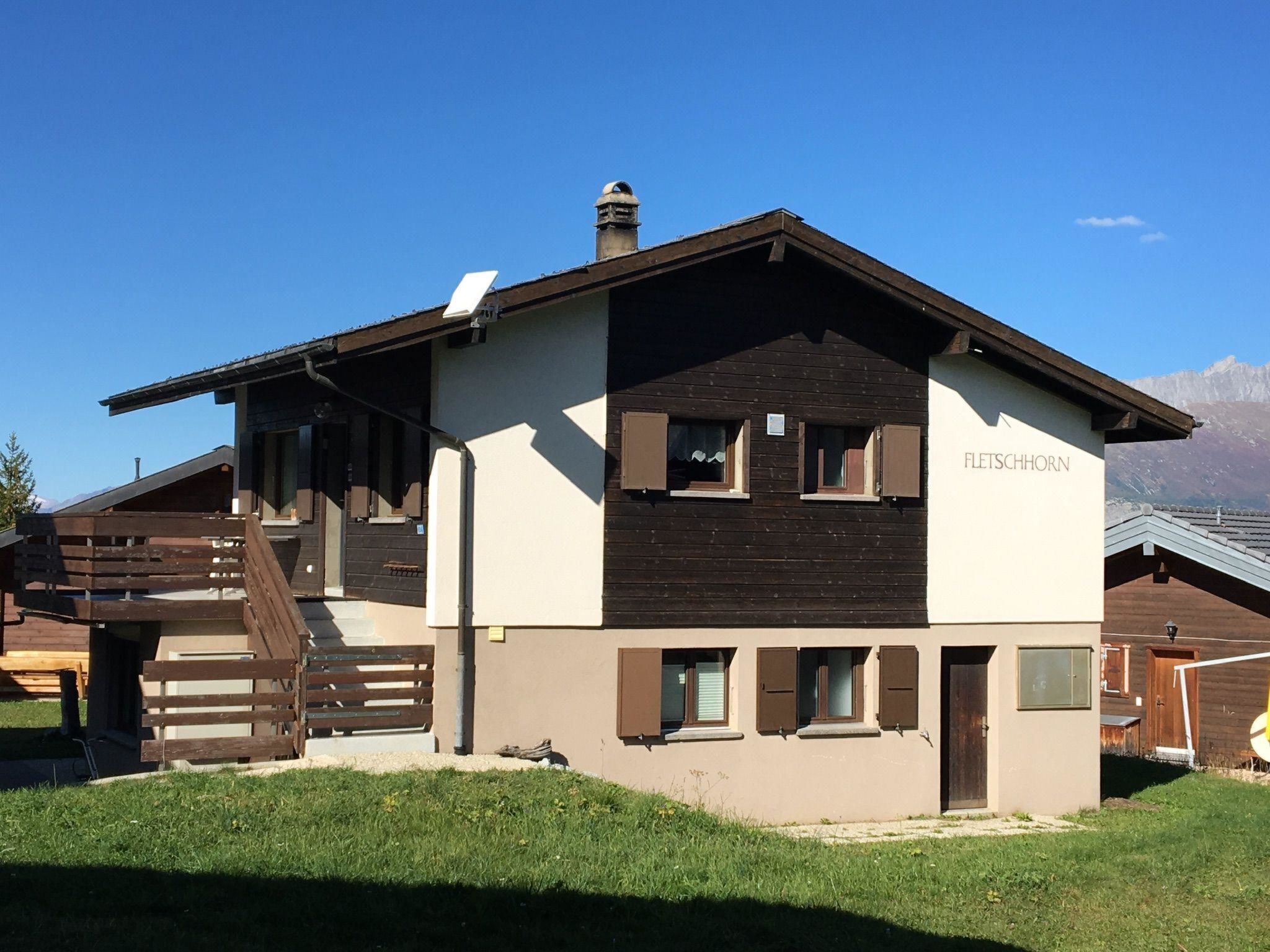 Un edificio de dos pisos con fachada de madera y un letrero que dice 'FLETSCHHORN'.