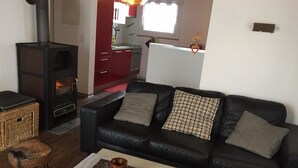 Ein Wohnzimmer mit einer schwarzen Ledersofa, einem kleinen Tisch mit einer Dekoration und einem Kamin.