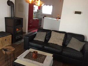 Ein Wohnzimmer mit einer schwarzen Ledersofa, einem kleinen Tisch mit einer Dekoration und einem Kamin.