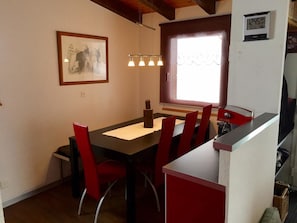 A dining area with a table, chairs, a window, and a wall-mounted clock. - Chalet Fletschhorn OG Appartement/Fewo, Dusche, WC 5-Bettwohnung by Interhome (Rosswald)