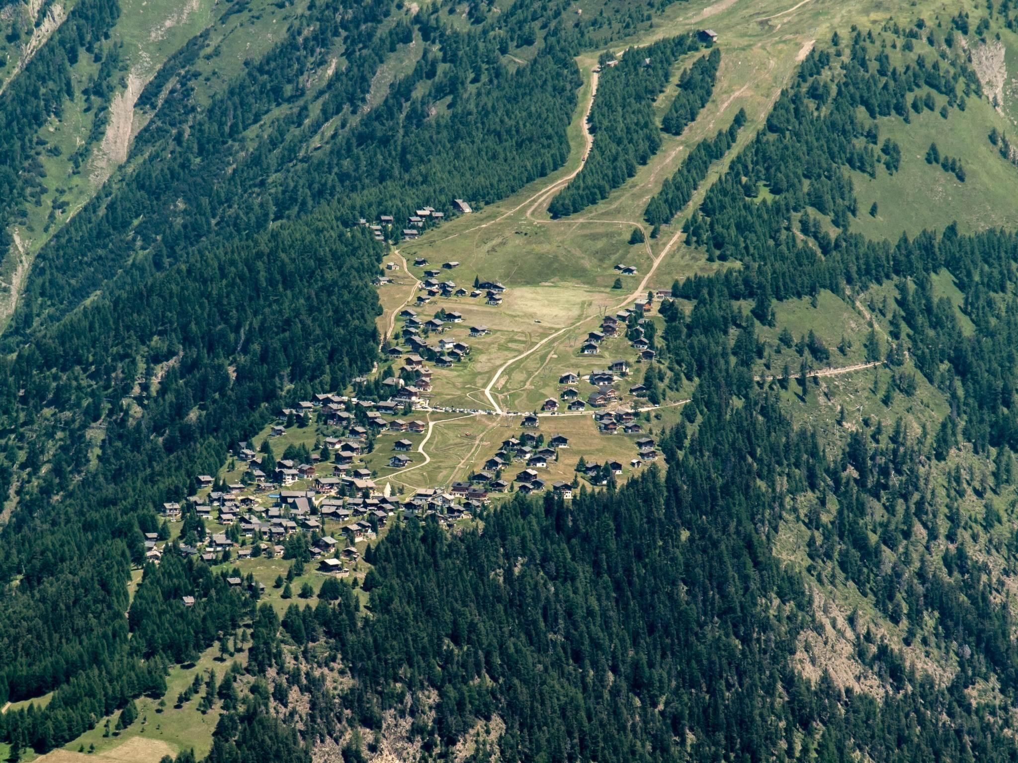 A mountainous area with a cluster of houses surrounded by dense forests and winding roads.