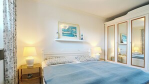 Ein Hotelzimmer mit einem großen Bett, zwei Nachttischlampen, einem Gemälde über dem Bett und einem Schrank mit Spiegeln.