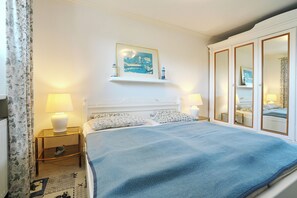 A hotel room with a large bed, two bedside lamps, a painting above the bed, and a wardrobe with mirrors. - Seebrücke Apartment 11 (Scharbeutz)