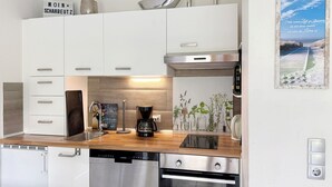 Una cocina moderna con armarios blancos, una cafetera y un lavavajillas Siemens.