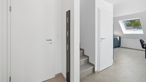 A modern interior with white walls, a staircase, and a skylight. - Modern "Ebbe&Flut" Vacation Rental in Norddeich for the Whole Family (Norddeich)