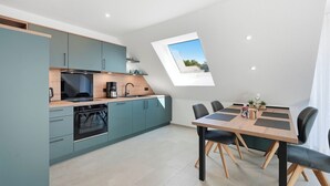 A modern kitchen with a dining area, a skylight, and a view of the outdoors. - Modern "Ebbe&Flut" Vacation Rental in Norddeich for the Whole Family (Norddeich)