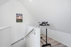 A staircase with a metal handrail, a wall-mounted picture, and a black coat rack. - Modern "Ebbe&Flut" Vacation Rental in Norddeich for the Whole Family (Norddeich)