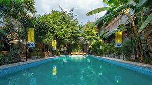 A swimming pool surrounded by lush greenery and yellow banners.