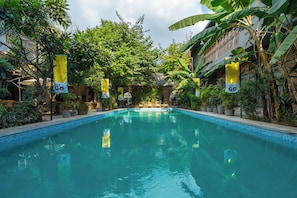 A swimming pool surrounded by lush greenery and yellow banners.