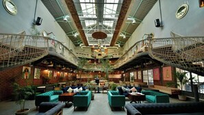 A spacious atrium with multiple levels, green seating areas, and a central staircase.