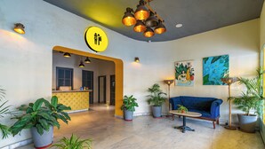 A modern lobby with a reception desk, seating area, and potted plants.
