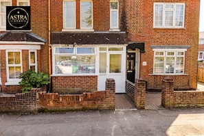 A two-story brick house with a visible front door, windows, and a car parked outside. - 3-Bed House Sleeps 5 · Free Parking · Walk to Southampton Common (Shirley)