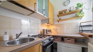 Eine Küche mit Spüle, Herd, Backofen und einer Uhr an der Wand.
