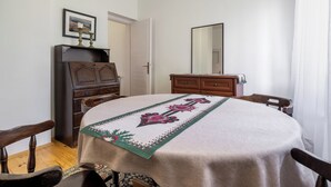 Ein Zimmer mit einem runden Tisch, zwei Stühlen, einem Holzschrank und einem Spiegel an der Wand.